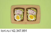 Making and eating rye bread sandwiches with avocado, egg, radish, greenery and black cumin seeds. Stop motion animation 4K video. Healthy eating concept. Стоковое видео, видеограф Мария Зубарева / Фотобанк Лори