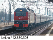 Электровоз ЭП2К-350 с пассажирским поездом на станции Славянка мартовским днем. Октябрьская железная дорога (2024 год). Редакционное фото, фотограф Виктор Карасев / Фотобанк Лори