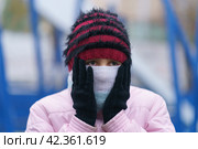 01/11/2019 - Москва, Россия, Teenager cold at the city street. She put on gloves, hat and covered her face, her cheeks with a scarf. Only the eyes are visible. Theme of the frost in the city. Стоковое фото, фотограф YuryKara / Фотобанк Лори