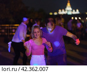 Moscow, Russia - August 20, 2019: Defocused photography of beautiful dancing people on the night party in the city street in  summer night.  Leisure, happiness and entertainment theme. Редакционное фото, фотограф YuryKara / Фотобанк Лори