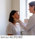 Laryngist examing throat of female patient visiting doctor in hospital. Стоковое фото, фотограф Natalia Gdovskaia / Фотобанк Лори