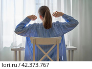 Unrecognizable woman stretching after long-hours working from ho. Стоковое фото, фотограф Natalia Gdovskaia / Фотобанк Лори