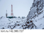 Зимний пейзаж с телебашней, антеннами и спутниковыми тарелками на вершине заснеженной горы. Связь и телекоммуникационная инфраструктура на Крайнем Севере России в Арктике. Стоковое фото, фотограф Андрей Степанов / Фотобанк Лори