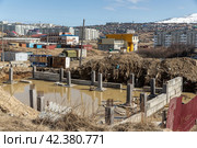 Строительная площадка с затопленными фундаментами и сваями. Приостановленое строительство здания. Рядом заброшенные недостроенные здания. Проблемы благоустройства и строительства в Сибири и на Дальнем Востоке. Город Магадан, Магаданская Область, Россия. (2021 год). Стоковое фото, фотограф Андрей Степанов / Фотобанк Лори