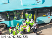 Группа детей в светоотражающих жилетах под присмотром взрослых сопровождающих заходит в автобус (2024 год). Редакционное фото, фотограф Станислав Кноп / Фотобанк Лори