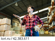 Thoughtful female storekeeper looking for tedious goods in building materials warehouse indoor. Стоковое фото, фотограф Яков Филимонов / Фотобанк Лори