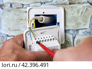 Connecting wires to wall thermostat for floor heating system, an electrician uses crosshead screwdriver for installation. Стоковое фото, фотограф Владимир Григорьев / Фотобанк Лори