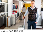 Positive man chose suitcase in haberdashery store. Стоковое фото, фотограф Яков Филимонов / Фотобанк Лори