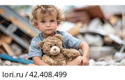 A little boy looks at the camera against the background of the destroyed houses of his city. He is holding a teddy bear in his hands. Стоковое AI-изображение, AI-художник Ярославский Максим / Фотобанк Лори