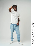 Young African Man Giving Thumbs Down Gesture Against a Neutral Background. Стоковое фото, фотограф Сергей Толмачёв / Фотобанк Лори