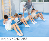 Underage boy practicing press in lying position with other attendees and trainer. Стоковое фото, фотограф Яков Филимонов / Фотобанк Лори