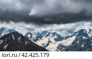 A dramatic scene, dark, heavy clouds loom over a mountain range, signaling approach of a storm. A pre-thunderstorm sky indicates that a cold snap and precipitation, rain, snow or hail, is imminent. Стоковое фото, фотограф Воловодов Владимир / Фотобанк Лори