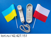 Flag of Ukraine, Poland and old corded telephone on a blue background, concept on the topic of telephone conversations between countries. Стоковое фото, фотограф Сергей Чайко / Фотобанк Лори