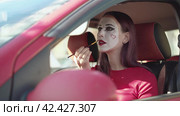 Mime in the car paints her lips with red lipstick winking at the camera. Стоковое видео, видеограф EStarodubov / Фотобанк Лори