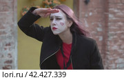 Mime girl in a black coat put a hand to her eyes in a search around herself. Стоковое видео, видеограф EStarodubov / Фотобанк Лори