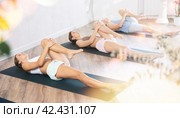 Teenage girl performing Ardha Pawanmuktasana stretching yoga asana. Стоковое фото, фотограф Яков Филимонов / Фотобанк Лори