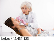 Mature woman beautician performing procedure of injection biorevitalization to young woman for alignment of facial asymmetry in esthetic clinic. Стоковое фото, фотограф Яков Филимонов / Фотобанк Лори