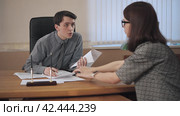 Business partners sitting at table conduct a dialogue and sign contracts. Стоковое видео, видеограф EStarodubov / Фотобанк Лори