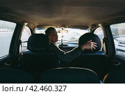 Водитель в салоне автомобиля оглядывается назад перед тем как поехать или припарковаться задним ходом. Стоковое фото, фотограф Константин Григорьев / Фотобанк Лори