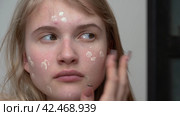 Woman applying cream foundation on her face using one finger can be useful for creating natural look. Стоковое видео, видеограф А. А. Пирагис / Фотобанк Лори