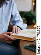 Brunette girl in a cafe drinking coffee, reading a book, close up. Стоковое фото, фотограф Александра Баранова / Фотобанк Лори