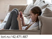 Девочка сидит на диване и смотрит видео на телефоне, играет в игры, ведет свою страницу в интернете, общается по видео с друзьями. Игровая зависимость. Стоковое фото, фотограф Наталья Бруштунова / Фотобанк Лори
