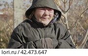 Бомж, бездомная женщина бродяга. Portrait of a homeless middle aged woman vagabond in a temporary place smiling at the camera. Стоковое видео, видеограф EStarodubov / Фотобанк Лори