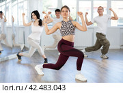 Young girl and group of positive people practicing energetic lindy hop movements at dance school. Стоковое фото, фотограф Яков Филимонов / Фотобанк Лори