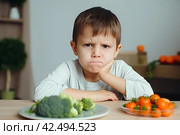 Boy showing disgust for fresh vegetables. Generate ai. Стоковое AI-изображение, AI-художник Иван Рябоконь / Фотобанк Лори