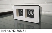 Перекидной циферблат часов будильника. Монтаж двух планов. Flip clock mechanism. 8:00 AM. Flip clock watch face. White brick wall in the background. Slow motion 240 fps. Стоковое видео, видеограф EStarodubov / Фотобанк Лори