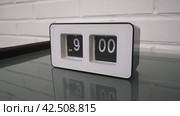 Перекидной циферблат часов будильника. Монтаж двух планов. Flip clock mechanism. 9:00 PM. Flip clock watch face. White brick wall in the background. Slow motion 240 fps. Стоковое видео, видеограф EStarodubov / Фотобанк Лори
