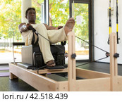 Activ middle-aged African-American man during pulling stretch band. Стоковое фото, фотограф Яков Филимонов / Фотобанк Лори