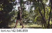 Девушка гуляет по парку. Монтаж двух кадров. Gorgeous beautiful blonde in a black dress walks along the park alley among the of trees. Close-up of female legs. Two shots editing. Steadicam shot. Стоковое видео, видеограф EStarodubov / Фотобанк Лори