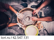 Woman and man working on the potter's wheel. Top view of hands making ceramic work. Стоковое фото, фотограф Константин Григорьев / Фотобанк Лори
