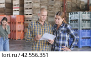 Man and woman workers with papers working at the storehouse. Стоковое видео, видеограф Яков Филимонов / Фотобанк Лори