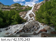 View of the Alibek waterfall formed by the fall of the Jalovchatka River from the Alibek glacier on a sunny summer day, Dombay, Karachay-Cherkessia, Russia. Стоковое фото, фотограф Ula Ulachka / Фотобанк Лори