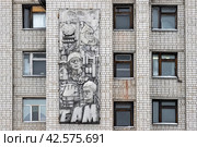На стене здания барельеф с надписью «БАМ». Металлический барельеф, посвящённый истории России и строительству Байкало-Амурской магистрали. Город Тында, Амурская область, Россия. (2024 год). Редакционное фото, фотограф Андрей Степанов / Фотобанк Лори