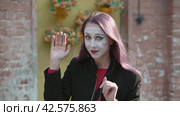 Знак рукой привет или прощай. Mime young woman in a black coat waving hand hi or farewell. Стоковое видео, видеограф EStarodubov / Фотобанк Лори