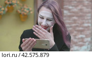 Веселый смех просматривая ролик на смартфоне. Mime young woman in a black coat laughs cheerfully while looking into a smartphone. Стоковое видео, видеограф EStarodubov / Фотобанк Лори