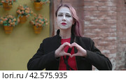 Изображает руками сердце и воздушный поцелуй. Mime girl in a black coat making heart shape out of the hands and then blowing a kiss. Happy Valentines Day. Стоковое видео, видеограф EStarodubov / Фотобанк Лори