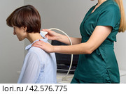 Faceless female sonographer examing neck. Healthcare worker doing ultrasound scanning. Стоковое фото, фотограф Natalia Gdovskaia / Фотобанк Лори