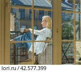 Happy elderly woman sitting on terrace with cup of coffee and enjoying sunny morning. Стоковое фото, фотограф Natalia Gdovskaia / Фотобанк Лори