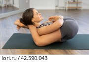 Pawanmuktasana yoga pose performed by slender girl in gym. Стоковое фото, фотограф Яков Филимонов / Фотобанк Лори