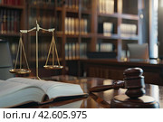 Books on jurisprudence, a judge's hammer and scales in the judge's office. The concept of justice. Стоковое AI-изображение, AI-художник Ярославский Максим / Фотобанк Лори