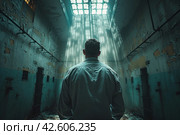 Rear view of a male in gray clothing, facing away from the camera, standing inside a jail cell with light shining through. ,    Generative AI. Стоковое AI-изображение, AI-художник Анна Кривицкая / Фотобанк Лори