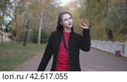 Mime young woman in a black coat walks down the street showing joking performance. Steadicam shot. Стоковое видео, видеограф EStarodubov / Фотобанк Лори