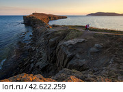 Мыс Тобизина, остров Русский, Приморский край, Россия. Японское море. Красивый вечерний морской пейзаж. Вид на скалы на берегу моря. По тропинке идут две девушки. Путешествия и туризм на Дальнем Востоке России. Природная достопримечательность. Стоковое фото, фотограф Андрей Степанов / Фотобанк Лори