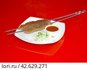 Шашлык из фарша, Люля-кебаб на белой тарелке с луком и соусом на зеркальном красном фоне. Стоковое фото, фотограф Михаил Киселев / Фотобанк Лори