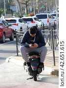 Мужчина на мотоцикле с телефоном в руках. A man on a motorcycle with a phone in his hands. (2022 год). Редакционное фото, фотограф Зимбачевский Виктор / Фотобанк Лори