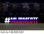 #Мы вместе. Фраза, сложенная из больших объемных световых букв, раскрашена в цвета российского флага. Подсвеченная вывеска на эспланаде на фоне многоэтажного дома со светящимися в ночи окнами. Пермь. Пермский Край. Россия. 2024. Редакционное фото, фотограф Бузмакова Светлана / Фотобанк Лори